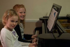 Children having fun learning to play piano